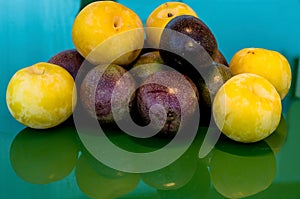 Pasiflora fruits and large yellow plums on on green glass table, selective focus