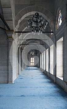 Passage in Nuruosmaniye Mosque with columns, arches and floor covered with blue carpet lighted by side windows, Istanbul, Turkey