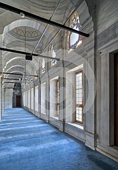 Passage in Nuruosmaniye Mosque with columns, arches and floor covered with blue carpet lighted by side windows, Istanbul, Turkey