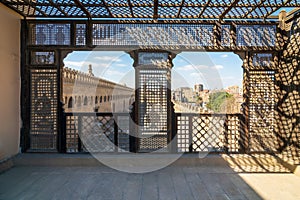 Passage surrounding the Mosque of Ibn Tulun framed by wooden window, Mashrabiya, Cairo, Egypt photo