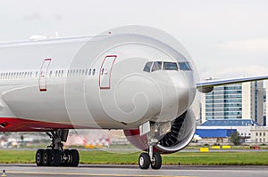 Passenger aircraft on the airport runway, against the backdrop of modern buildings city.