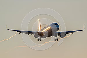 Passenger aircraft approaching to the airport early morning with sun reflections on it\'s body