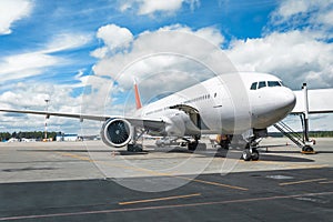 Passenger aircraft with boarding stairs, waiting for boarding passengers and baggage before the flight, summer airport trip