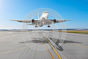 Passenger aircraft with a cast shadow on the asphalt landing on a runway airport, motion blur.