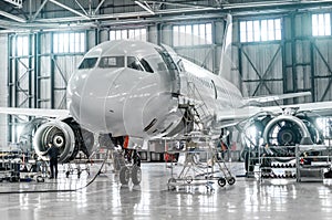 Passenger aircraft on maintenance of engine and fuselage repair in airport hangar.