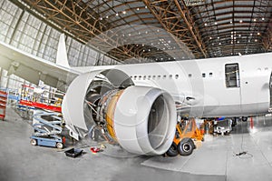 Passenger aircraft on maintenance of engine and fuselage repair in airport hangar. View airplane engine.