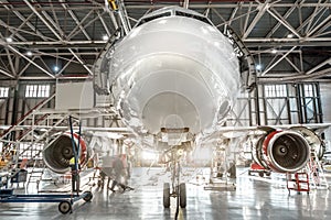 Passenger aircraft, nose close up. Maintenance of engine and fuselage repair in airport hangar