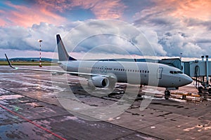 Passenger aircraft parked to a boarding bridge in the evening light