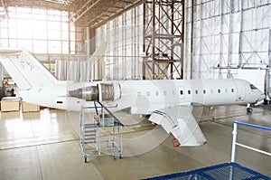 Passenger aircraft, side view - on maintenance of engine on tail and fuselage repair in airport hangar.