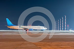 The passenger airliner moves behind the follow-me car at the night ariport apron