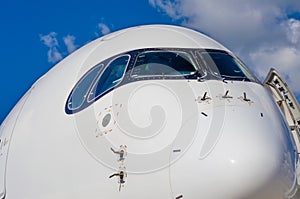 Passenger airplane nose cockpit in blue clouds sky