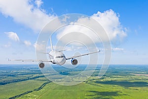 Passenger airplane flies above the clouds and forest fields landscape, aerial view