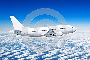 Passenger airplane fly on a hight above clouds and blue sky.