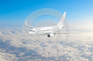 Passenger airplane fly on a hight above clouds and blue sky.