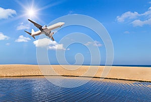 passenger airplane flying above tropical beach in andaman sea on blue sky with sunlight