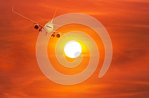 Passenger airplane flying away in to sky high altitude above the sun during sunset