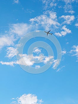 The passenger airplane is flying far away in the blue sky and white clouds. Aircraft in the air. International passenger air