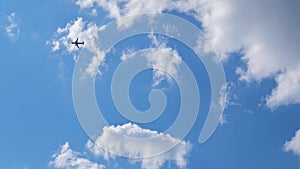 The passenger airplane is flying far away in the blue sky and white clouds. Aircraft in the air. Light background or backdrop