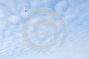 The passenger airplane is flying far away in the blue sky and white clouds. Aircraft in the air. Light background or wallpaper
