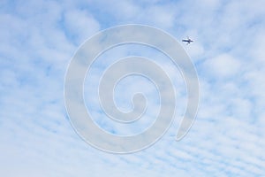 The passenger airplane is flying far away in the blue sky and white clouds. Aircraft in the air. Light background or wallpaper