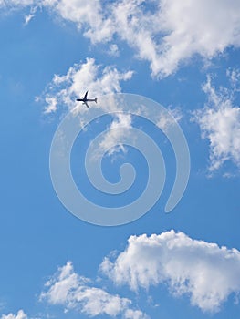 The passenger airplane is flying far away in the blue sky and white clouds. Aircraft in the air. Light vertical background or