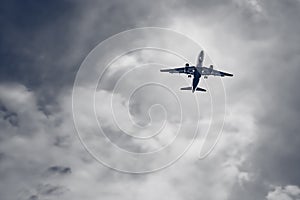 Passenger airplane flying on storm dark clouds background