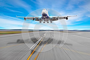 Passenger airplane four engine with a cast shadow on the asphalt landing on a runway airport.