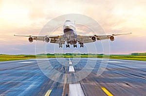 Passenger airplane landing at sunset on a runway.