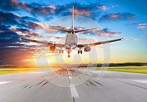 Passenger airplane landing at sunset on a runway.