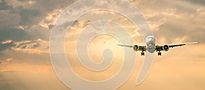 Passenger airplane. Landscape with Front of white airplane is flying in the orange sky with clouds, Passenger aircraft is landing