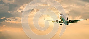 Passenger airplane. Landscape with Front of white airplane is flying in the orange sky with clouds, Passenger aircraft is landing