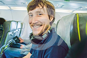 Passenger in airplane using headphones. man in plane cabin listening to music on headphones.