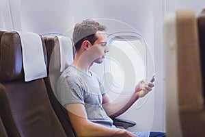 Passenger of airplane using mobile smart phone in the plane, travel app