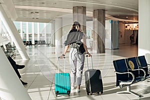 Passenger with baggage going to boarding plane in light airport with panoramic windows and rolling suitcases with