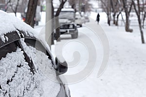 Passenger car with snowflakes at snowy overcast weather, side door with snow close up, urban landscape at cold snowfall