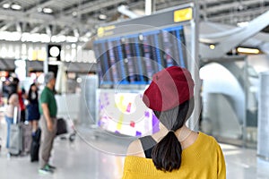 Passenger checking flight status at airport information display, Asian traveler looking at departure and arrival board.