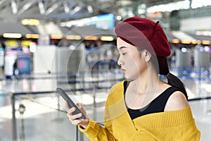 Passenger checking flight status and make a self check-in on application smartphone at the airport.