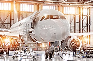 Passenger commercial airplane on maintenance of engine turbo jet and fuselage repair in airport hangar. Aircraft with open hood on