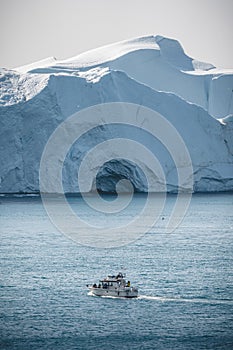 Passenger cruise ship sailing through the icy waters of arctic landscape in Ilulissat, Greenland. A small boat among