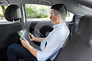 Passenger with earphones and tablet pc in taxi car