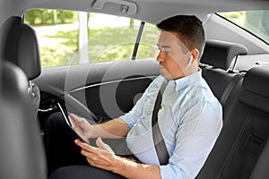 Passenger with earphones and tablet pc in taxi car