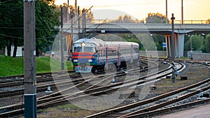 A passenger electric train passes by the railway during sunset. A major railway interchange on the territory of the station. A