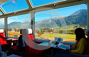 A passenger enjoying the idyllic scenery of Swiss countryside through the wide panoramic windows