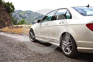 Passenger expensive white car on a dusty country road