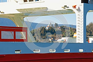 Passenger ferry boat at coast of bay. Montenegro, Bay of Kotor. View of Kamenari village with Church of Saint Nedelja