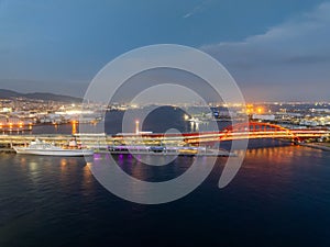 Passenger ferry docked along red arched bridge and city lights at night photo