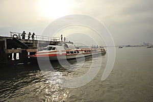passenger ferry docked at pier people disembarking calm water hazy sky