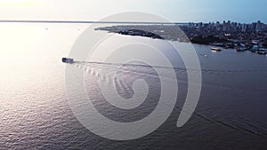 Passenger ferry leaving the city of Belem on a big brown colored river City skyline in the background Aerial Video