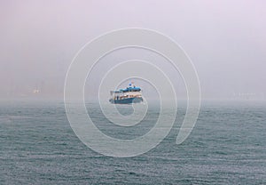 Passenger ferry navigates through fog in whiteout conditions on rainy day photo