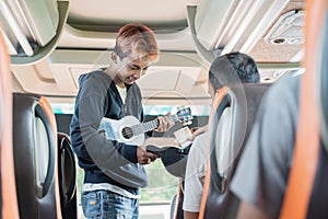 a passenger gives money to a busker wearing an ukulele photo